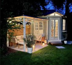 a small backyard with a gazebo and seating area at night, lit up by lights