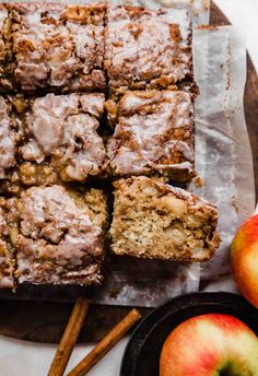 apple cinnamon coffee cake sliced on top of a cutting board next to apples and cinnamon sticks