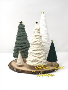 three small christmas trees sitting on top of a tree stump in front of a white background