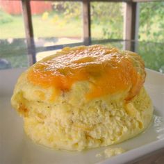 an omelet on a plate in front of a window with grass and trees