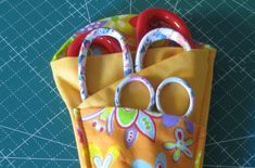 a yellow bag with two pairs of scissors in it sitting on a blue tablecloth