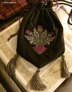 a bag sitting on top of an open book with tassels hanging from it