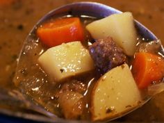 a spoon full of stew with potatoes and carrots