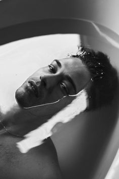 a man laying in a bathtub with his head on the edge of the tub