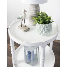 a white table with a bird on top and a plant in a vase next to it