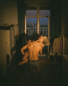 a man is standing in front of a window with his back turned to the camera