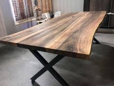 a large wooden table sitting on top of a gray carpeted floor next to a window