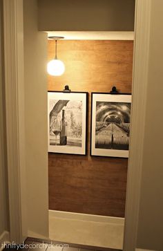 two pictures are hanging on the wall in a hallway with wood paneling and white trim