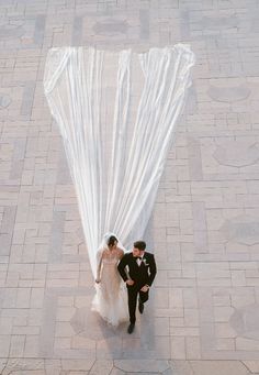 a man and woman standing next to each other in front of a large white object