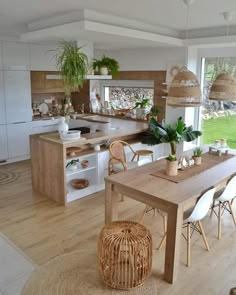 an open kitchen and dining room with lots of natural wood furniture in the middle of it