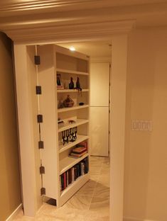 an empty room with bookshelves and shelves in the corner, as well as a door leading to another room