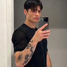 a man taking a selfie in the mirror with his cell phone and tattoos on his arm