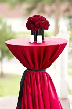 a red table topped with a vase filled with flowers