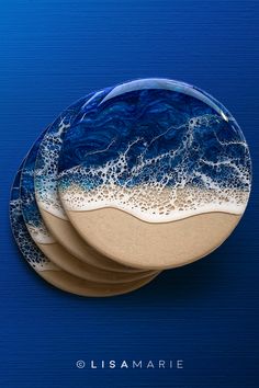 three blue and white plates sitting on top of a blue surface with waves in the water