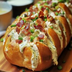 a long loaf of bread with bacon and cheese on it sitting on a cutting board