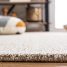 a close up view of a rug on the floor in front of a bed with pillows