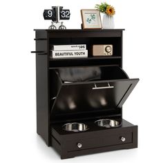 an open black cabinet with two bowls in it and some pictures on the top shelf