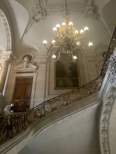 an ornate staircase with chandelier and paintings on the walls