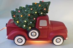 a red toy truck with a christmas tree on the back and lights in the bed