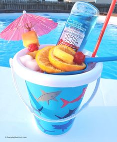 a cup filled with fruit next to a swimming pool