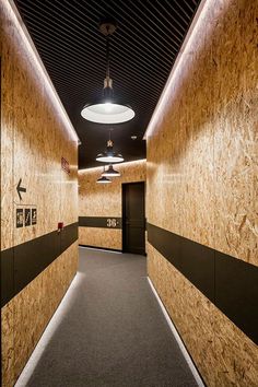 an empty hallway with wood paneling and black trim on the walls is lit by recessed lights