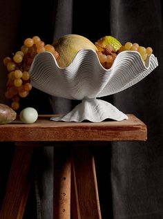 a white bowl filled with fruit on top of a wooden table