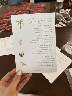 a person holding up a menu at a table with other items on it in front of them