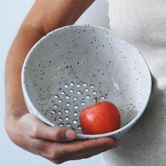 a person holding a bowl with an apple in it