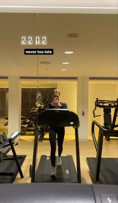 a woman is running on a treadmill in the gym while looking at her cell phone