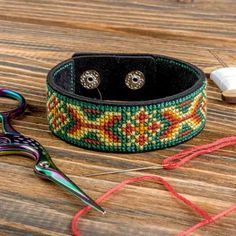 a pair of scissors sitting on top of a table next to some beads and thread