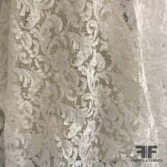 an image of white lace fabric with flowers on the bottom and back side, close up