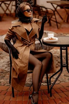 a woman in a trench coat sitting at a table