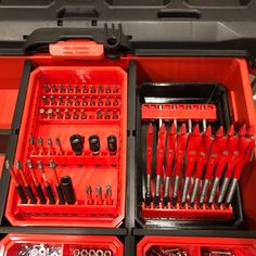 the toolbox is full of tools and screwdrives in red trays with black handles