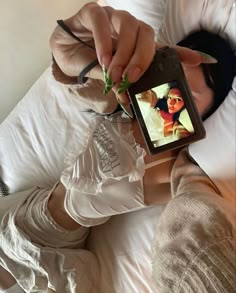 a woman laying in bed while holding an electronic device