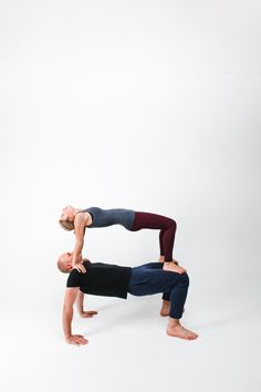 two people doing yoga poses in front of a white background