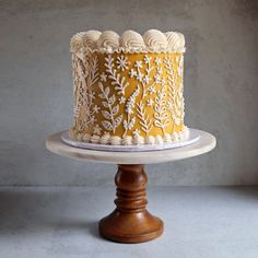 a yellow and white cake sitting on top of a wooden stand