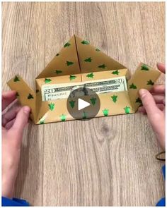 an origami dollar bill is being folded into a paper pyramid with green leaves on it