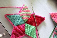 two crocheted stars are sitting next to each other on a table with knitting needles