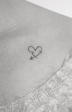 a small heart with an arrow tattoo on the side of a woman's stomach