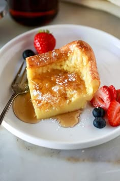 a piece of cake on a plate with berries and syrup