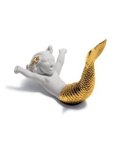 a white and gold mermaid figurine laying on its back with her legs spread out