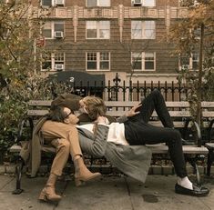 two people sitting on a bench in front of a building