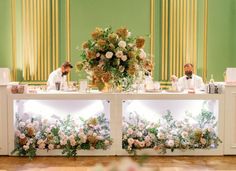 two men sitting at a table with flowers on it