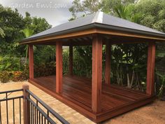 a wooden gazebo sitting on top of a lush green field