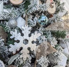 a snowflake ornament is hanging on a christmas tree with other ornaments