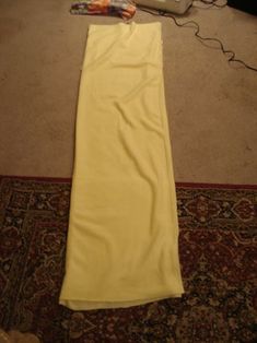 a long yellow dress laying on the floor next to a lamp and carpeted area