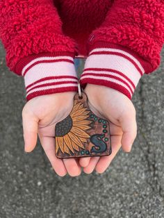 a person is holding their hand with a wooden sunflower decoration on it's thumb