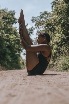 a woman is sitting on the ground with her legs up in the air while stretching