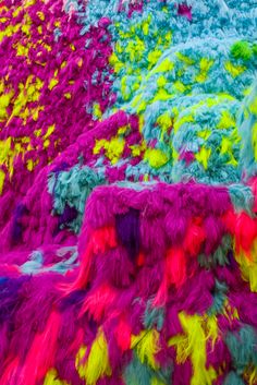 multicolored shaggy rugs on display in an art gallery, with multiple colors