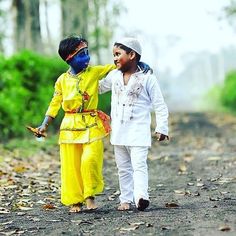 two children walking down a dirt road with painted faces on their face and hands in the air